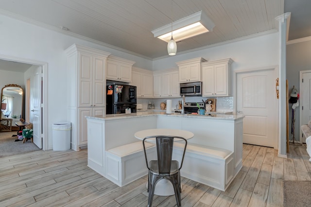 kitchen featuring light wood-style floors, decorative light fixtures, crown molding, a center island with sink, and appliances with stainless steel finishes