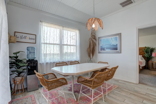 dining space with light wood-type flooring, baseboards, visible vents, and crown molding