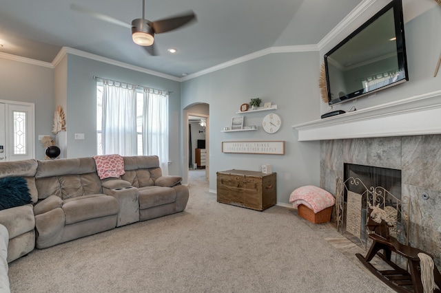carpeted living area with arched walkways, a wealth of natural light, crown molding, and ceiling fan