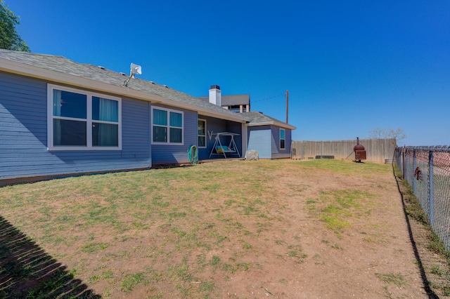 rear view of property featuring a lawn and a fenced backyard