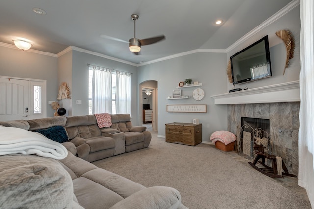 living room with arched walkways, carpet floors, crown molding, a fireplace, and ceiling fan