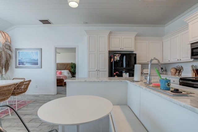 kitchen with light wood finished floors, electric range, visible vents, baseboards, and freestanding refrigerator