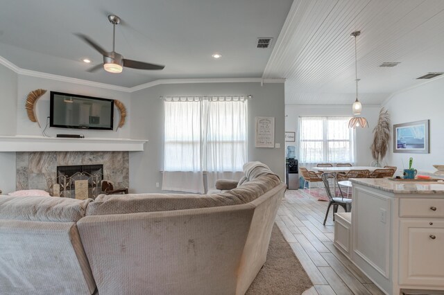living room with ceiling fan, crown molding, visible vents, and light wood-type flooring