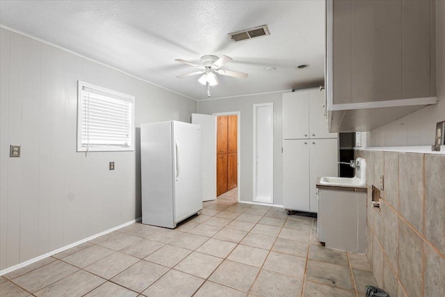 kitchen featuring sink, white cabinets, white fridge, ceiling fan, and a textured ceiling