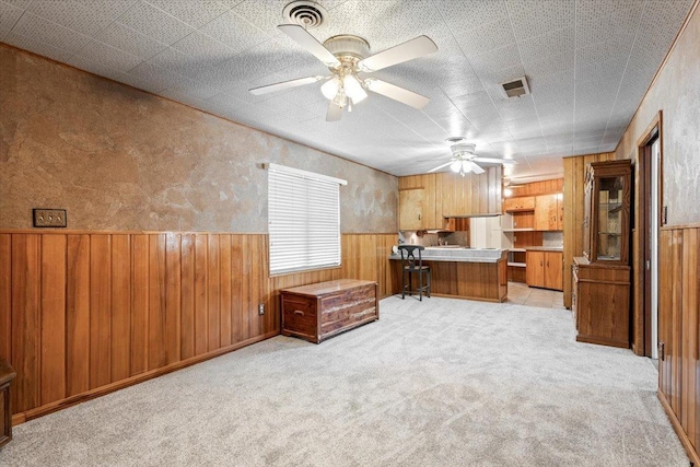 unfurnished office with ceiling fan, light carpet, and wooden walls