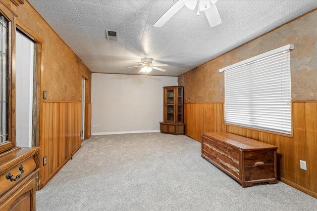 sitting room featuring ceiling fan, light carpet, and wooden walls