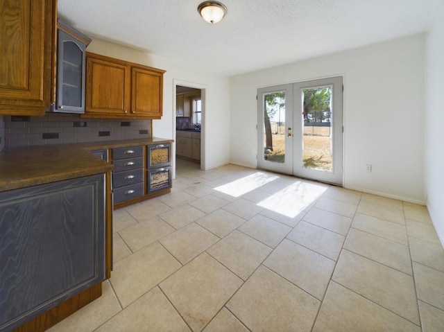 kitchen with tasteful backsplash, light tile patterned floors, french doors, and a textured ceiling