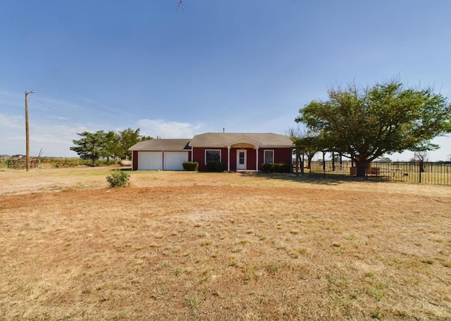 ranch-style house with a garage, a front yard, and a rural view