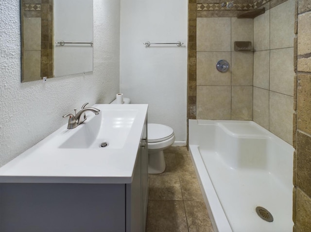 bathroom with vanity, toilet, and a tile shower