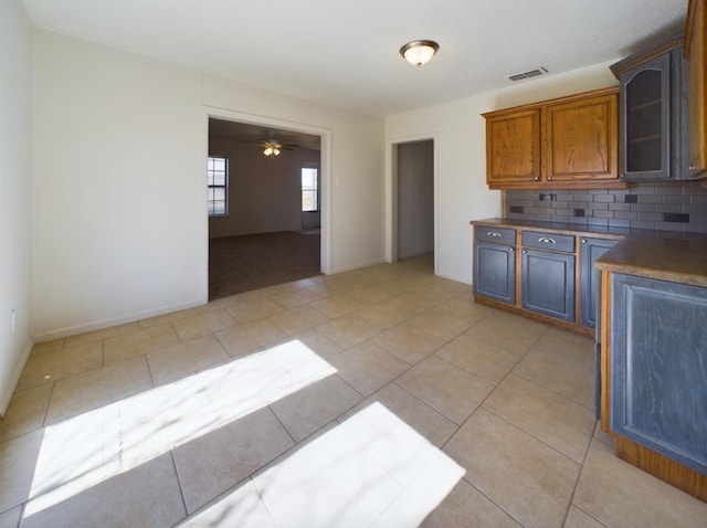 kitchen featuring ceiling fan, light tile patterned floors, and backsplash