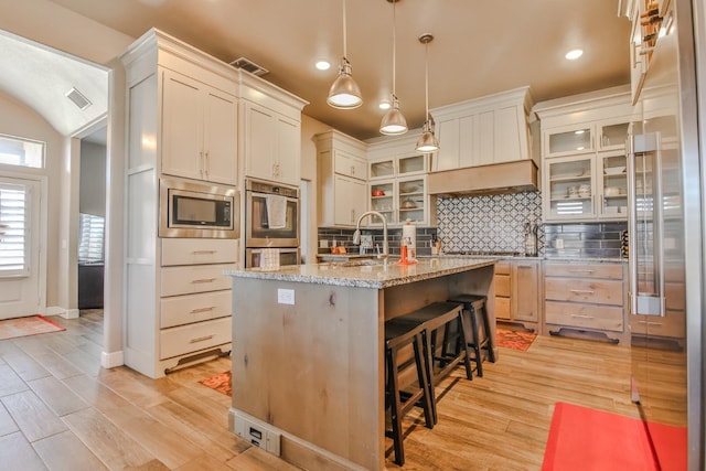 kitchen with pendant lighting, sink, a kitchen island with sink, stainless steel appliances, and decorative backsplash