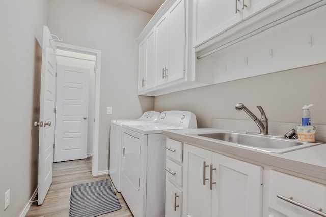 washroom featuring separate washer and dryer, sink, light hardwood / wood-style floors, and cabinets