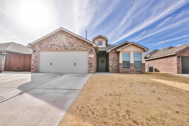 ranch-style home featuring brick siding, central air condition unit, an attached garage, and driveway