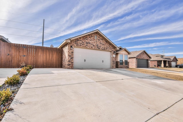 single story home with concrete driveway, fence, brick siding, and a garage