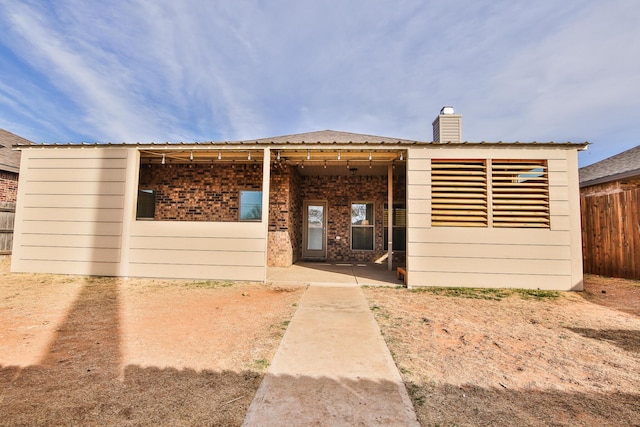 doorway to property featuring fence, brick siding, and a chimney