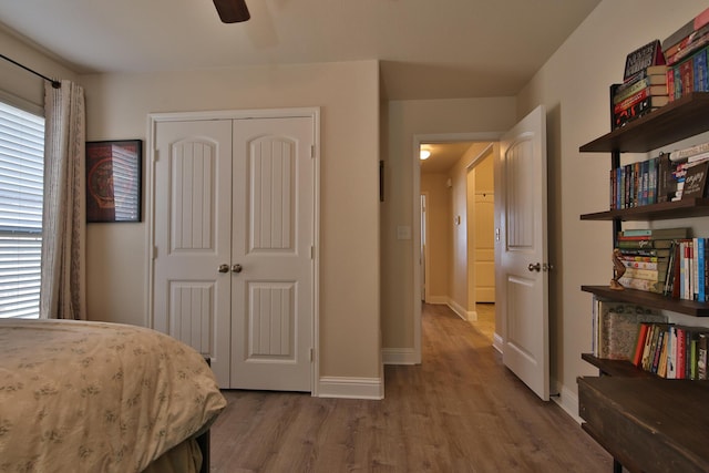 bedroom with a closet, a ceiling fan, baseboards, and wood finished floors