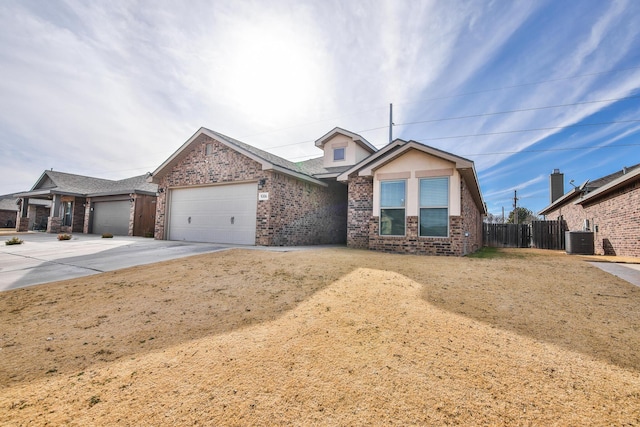 view of front of home with driveway, fence, a garage, brick siding, and central AC unit