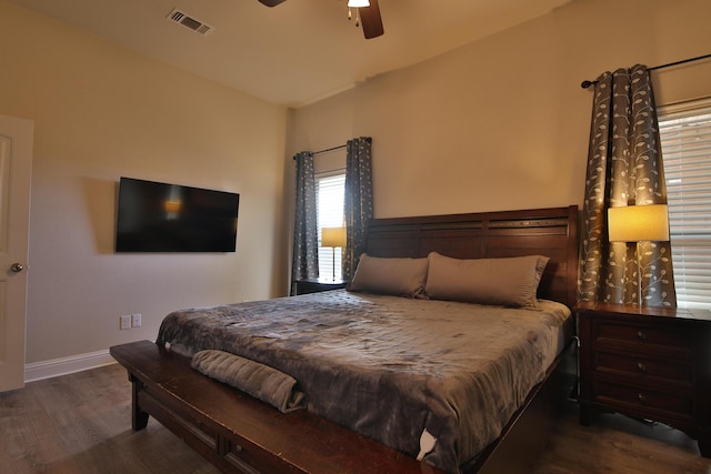 bedroom with ceiling fan, wood finished floors, visible vents, and baseboards