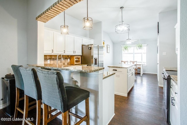 1308 Nottingham Ave, Wolfforth, TX 79382 - kitchen with stainless steel fridge, range with electric stovetop, a peninsula, a kitchen island, and backsplash