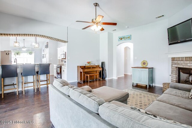 1308 Nottingham Ave, Wolfforth, TX 79382 - living room with arched walkways, a ceiling fan, wood finished floors, and a fireplace