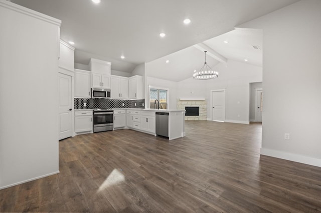 kitchen featuring sink, white cabinetry, decorative light fixtures, lofted ceiling with beams, and stainless steel appliances