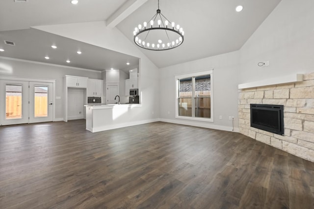 unfurnished living room with dark wood-type flooring, a wealth of natural light, a notable chandelier, and a fireplace