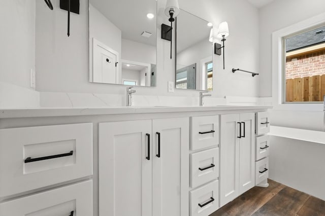 bathroom with hardwood / wood-style flooring, vanity, and a bath