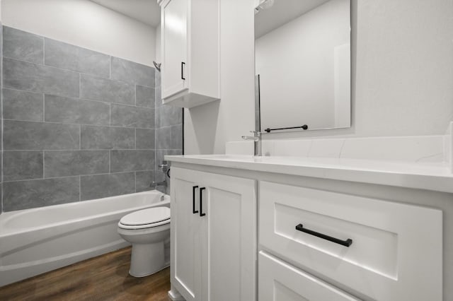 full bathroom with tiled shower / bath, hardwood / wood-style floors, vanity, and toilet