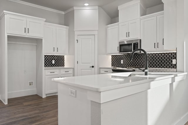 kitchen with backsplash, ornamental molding, dark wood-type flooring, and white cabinets