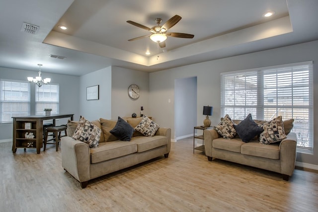 living room with a tray ceiling and light hardwood / wood-style flooring