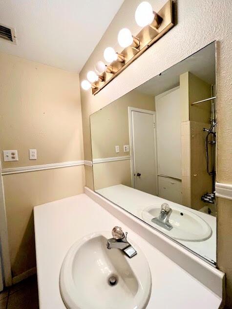 bathroom featuring visible vents, vanity, and walk in shower