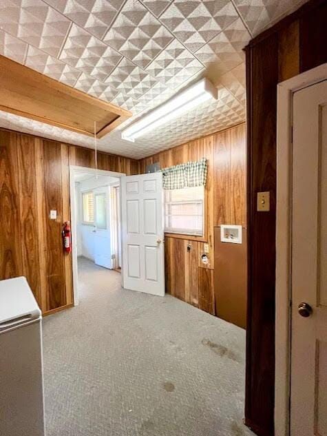 corridor featuring wood walls, carpet, and attic access