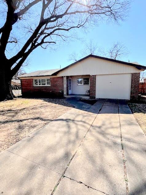 view of front facade featuring brick siding, driveway, and an attached garage