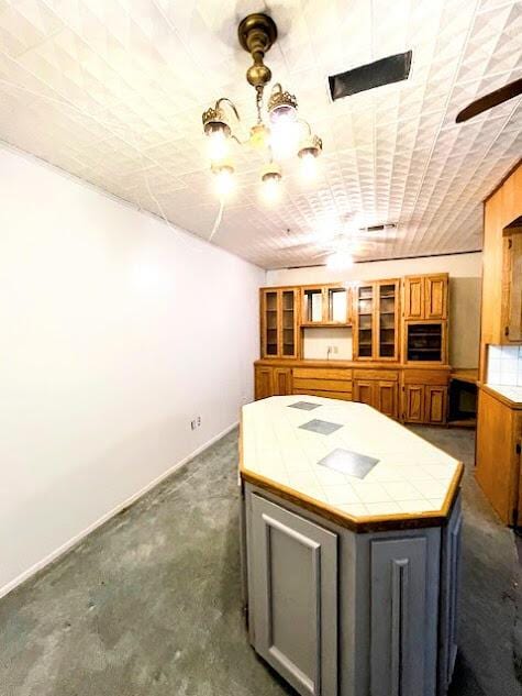 kitchen featuring baseboards, tile counters, and gray cabinetry