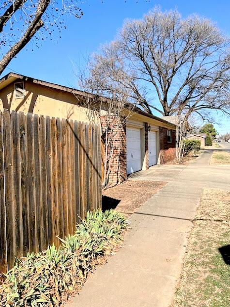 view of side of property with a garage, fence, and driveway