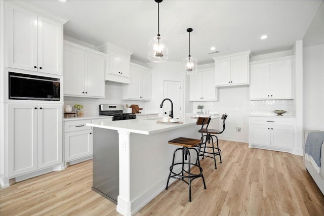 1406 Durham Ave, Wolfforth, TX 79382 - kitchen with stove, black microwave, tasteful backsplash, white cabinets, and recessed lighting