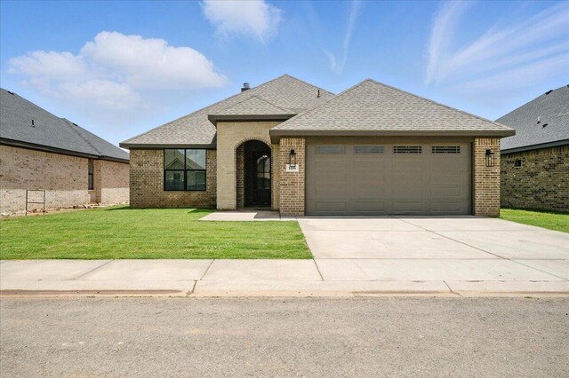 1406 Durham Ave, Wolfforth, TX 79382 - french country home featuring brick siding, concrete driveway, a garage, a front lawn, and a shingled roof