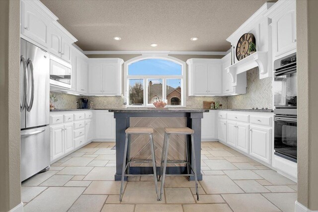 kitchen with stainless steel fridge, white cabinetry, a kitchen breakfast bar, a center island, and built in microwave