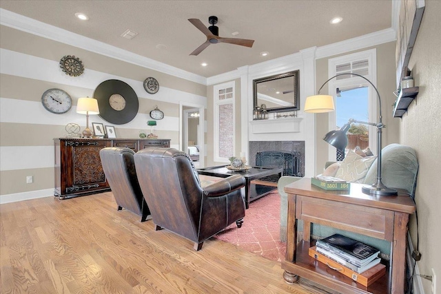 living room with crown molding, light hardwood / wood-style flooring, and ceiling fan