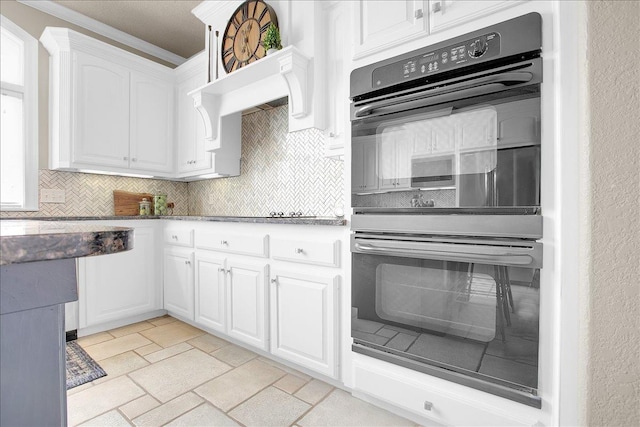 kitchen featuring white cabinetry, crown molding, double oven, stone counters, and decorative backsplash