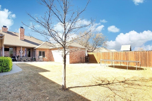 view of yard with a trampoline and a patio area