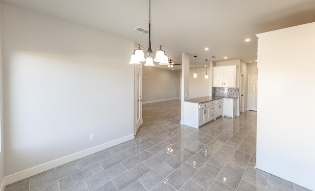 kitchen featuring white cabinetry, pendant lighting, a notable chandelier, and decorative backsplash