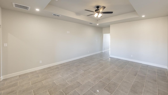 spare room with ceiling fan and a tray ceiling