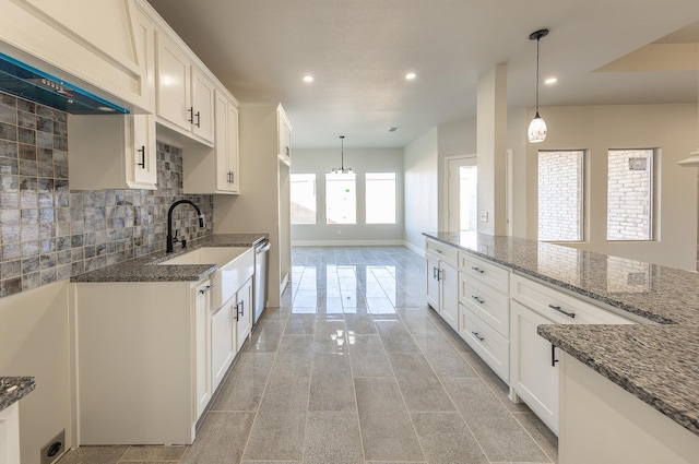 kitchen featuring pendant lighting, sink, white cabinets, decorative backsplash, and dark stone counters