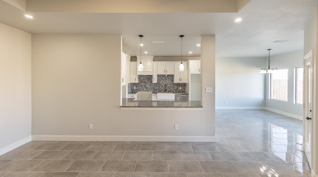 kitchen with decorative light fixtures, tasteful backsplash, dark stone countertops, white cabinets, and kitchen peninsula