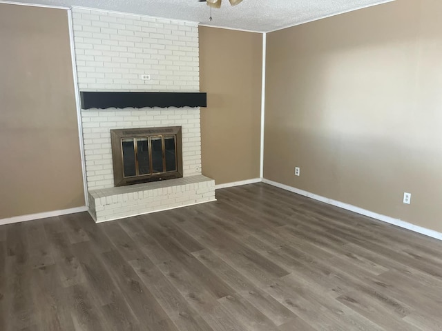 unfurnished living room with a brick fireplace, dark hardwood / wood-style floors, a textured ceiling, and ceiling fan