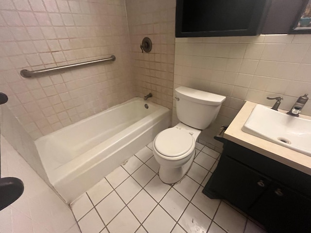 full bathroom featuring tile patterned floors, toilet, tiled shower / bath, tile walls, and vanity