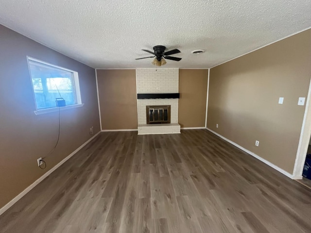 unfurnished living room with ceiling fan, a brick fireplace, a textured ceiling, and dark hardwood / wood-style flooring