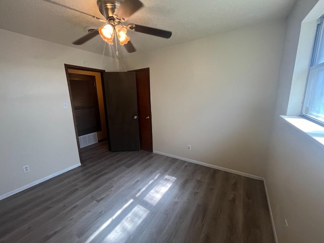 empty room with ceiling fan, dark hardwood / wood-style floors, and a textured ceiling