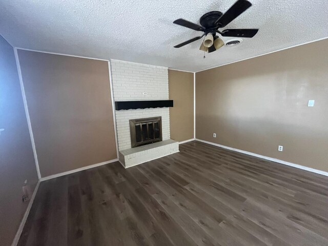 unfurnished living room with dark wood-type flooring, ceiling fan, a fireplace, and a textured ceiling